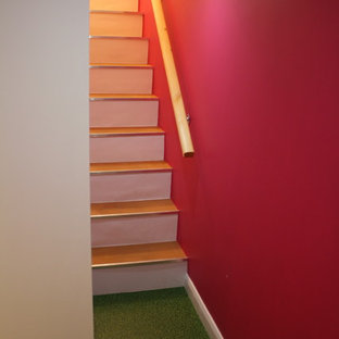 This is an example of a medium sized bohemian basement in Manchester with pink walls, vinyl flooring, a standard fireplace, a stone fireplace surround and green floors.
