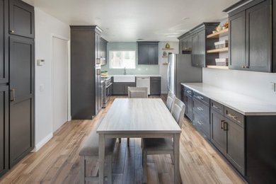 Inspiration for a mid-sized transitional u-shaped ceramic tile and brown floor eat-in kitchen remodel in Los Angeles with a farmhouse sink, shaker cabinets, brown cabinets, quartz countertops, green backsplash, ceramic backsplash, stainless steel appliances and white countertops