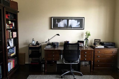 Example of a mid-sized minimalist freestanding desk dark wood floor and black floor study room design in Houston with beige walls