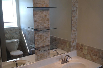 Bathroom - mid-sized transitional 3/4 porcelain tile bathroom idea in St Louis with raised-panel cabinets, dark wood cabinets, a two-piece toilet, beige walls, an integrated sink, solid surface countertops and white countertops