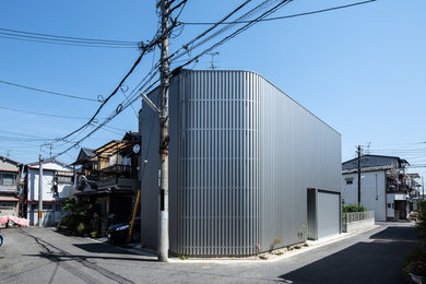 Photo of a mid-sized modern two-storey grey house exterior in Osaka with metal siding, a flat roof and a metal roof.