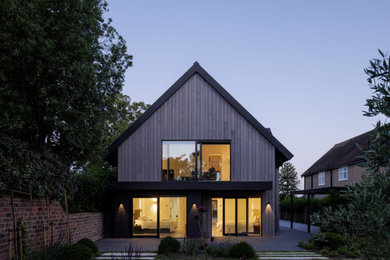 Diseño de fachada de casa gris y gris actual de dos plantas con revestimiento de madera, tejado a dos aguas, tejado de metal y panel y listón