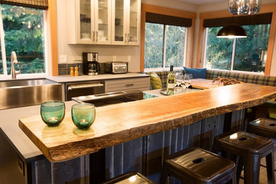 Inspiration for a mid-sized rustic galley porcelain tile and gray floor open concept kitchen remodel in Seattle with a farmhouse sink, raised-panel cabinets, black cabinets, solid surface countertops, stainless steel appliances and an island