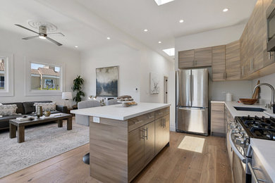 Mid-sized minimalist l-shaped light wood floor, brown floor and vaulted ceiling open concept kitchen photo in Los Angeles with an undermount sink, flat-panel cabinets, light wood cabinets, quartzite countertops, white backsplash, stainless steel appliances, an island, white countertops and ceramic backsplash