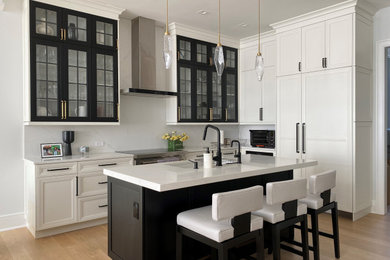Inspiration for a modern light wood floor and beige floor kitchen remodel in New York with white backsplash, stainless steel appliances, an island, white countertops, an undermount sink and white cabinets