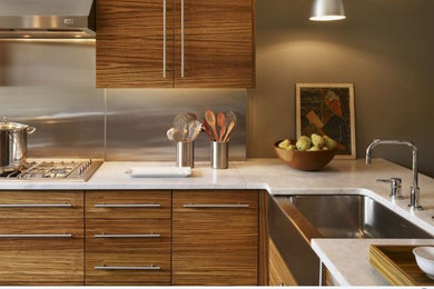 This is an example of a mid-sized modern l-shaped eat-in kitchen in San Francisco with flat-panel cabinets, medium wood cabinets, metallic splashback, metal splashback, stainless steel appliances, no island and white benchtop.