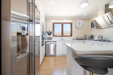 Design ideas for a large modern u-shaped separate kitchen in Alicante-Costa Blanca with an undermount sink, flat-panel cabinets, white cabinets, quartz benchtops, white splashback, terra-cotta splashback, stainless steel appliances, ceramic floors, a peninsula, brown floor and white benchtop.