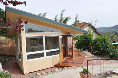 Small contemporary beige one-story stucco exterior home idea in San Luis Obispo with a metal roof
