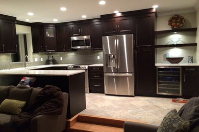 Large trendy u-shaped porcelain tile and beige floor open concept kitchen photo in Vancouver with an undermount sink, recessed-panel cabinets, dark wood cabinets, quartz countertops, gray backsplash, stainless steel appliances and a peninsula