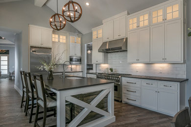 Kitchen - contemporary dark wood floor kitchen idea in Austin with an undermount sink, shaker cabinets, white cabinets, laminate countertops, white backsplash, subway tile backsplash, stainless steel appliances and an island