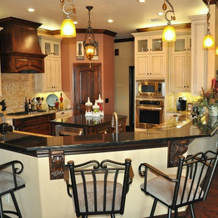 Mid-sized traditional kitchen pantry ideas - Example of a mid-sized classic l-shaped ceramic floor kitchen pantry design in Oklahoma City with an undermount sink, raised-panel cabinets, distressed cabinets, granite countertops, beige backsplash, mosaic tile backsplash, stainless steel appliances and an island