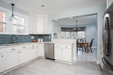 Inspiration for a mid-sized transitional u-shaped vinyl floor eat-in kitchen remodel in Other with an undermount sink, shaker cabinets, white cabinets, quartz countertops, blue backsplash, glass tile backsplash, stainless steel appliances and a peninsula