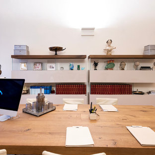 フィレンツェの大きいモダンスタイルのおしゃれな書斎 (白い壁、テラコッタタイルの床、標準型暖炉、コンクリートの暖炉まわり、自立型机、茶色い床) の写真