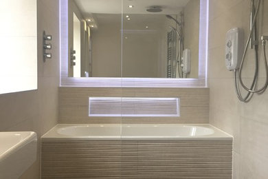 Photo of a mid-sized contemporary kids wet room bathroom in Dublin with a drop-in tub, a wall-mount toilet, beige tile, ceramic tile, beige walls, porcelain floors, a wall-mount sink, brown floor and an open shower.