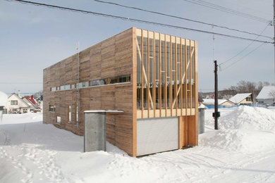 Ejemplo de fachada de casa marrón moderna de dos plantas con revestimiento de madera y tejado plano