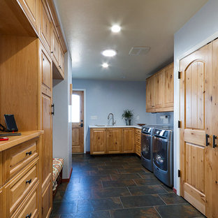 フェニックスのサンタフェスタイルのおしゃれな洗濯室 (アンダーカウンターシンク、レイズドパネル扉のキャビネット、中間色木目調キャビネット、木材カウンター、青い壁、磁器タイルの床、左右配置の洗濯機・乾燥機) の写真