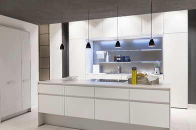 Mittelgroße Moderne Küche in L-Form mit Einbauwaschbecken, flächenbündigen Schrankfronten, weißen Schränken, Küchenrückwand in Grau, Kücheninsel, grauem Boden und weißer Arbeitsplatte in München