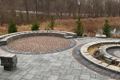Huge backyard stone patio photo in DC Metro with a fire pit and a pergola