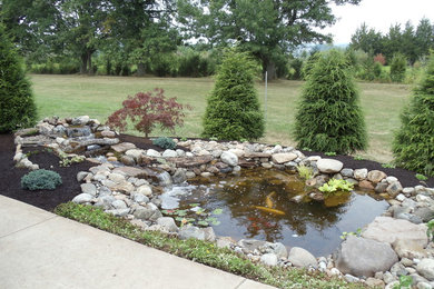 Photo of a large contemporary backyard stone water fountain landscape in Philadelphia.