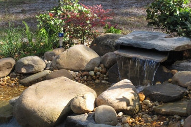 This is an example of a mid-sized transitional full sun front yard water fountain landscape in Tampa for spring.