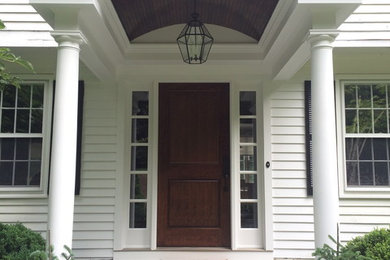 This is an example of a traditional front door in New York with a dark wood front door and a single front door.