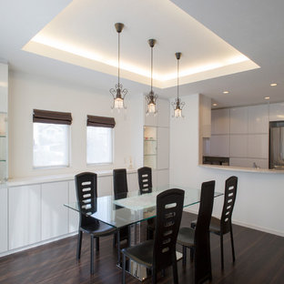 Inspiration pour une salle à manger ouverte sur la cuisine minimaliste de taille moyenne avec un mur blanc, un sol en contreplaqué et un sol marron.