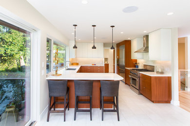 Photo of a contemporary u-shaped eat-in kitchen in Vancouver with a double-bowl sink, flat-panel cabinets, medium wood cabinets, beige splashback and stainless steel appliances.