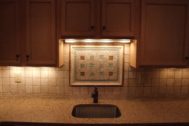 Photo of a small transitional kitchen in New York with an undermount sink, recessed-panel cabinets, beige cabinets, solid surface benchtops, multi-coloured splashback and mosaic tile splashback.