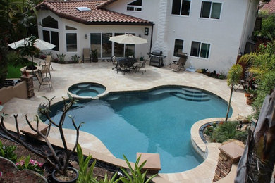 Photo of a mid-sized traditional backyard custom-shaped pool in San Diego with a hot tub and concrete pavers.