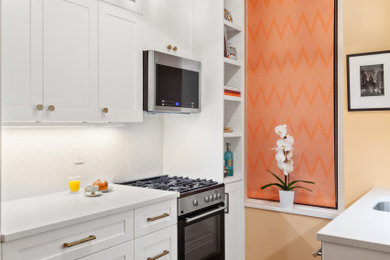 ニューヨークにある高級な小さなコンテンポラリースタイルのおしゃれなキッチン (シングルシンク、シェーカースタイル扉のキャビネット、白いキャビネット、人工大理石カウンター、白いキッチンパネル、磁器タイルのキッチンパネル、シルバーの調理設備、ライムストーンの床、アイランドなし、黒い床、白いキッチンカウンター) の写真