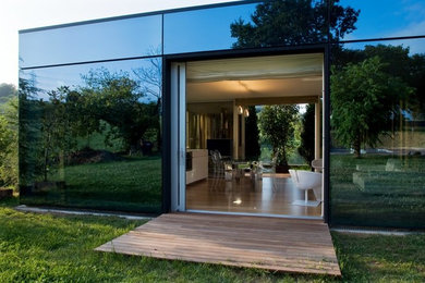 Mid-sized contemporary one-storey glass exterior in Other with a flat roof.