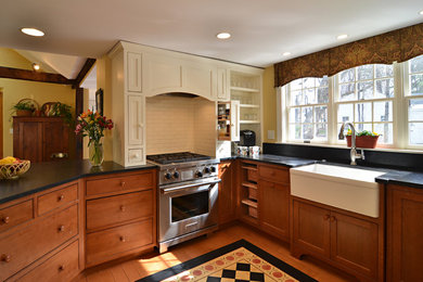 Mid-sized cottage u-shaped medium tone wood floor open concept kitchen photo in Boston with a farmhouse sink, shaker cabinets, medium tone wood cabinets, terrazzo countertops, black backsplash, stone slab backsplash, stainless steel appliances and a peninsula