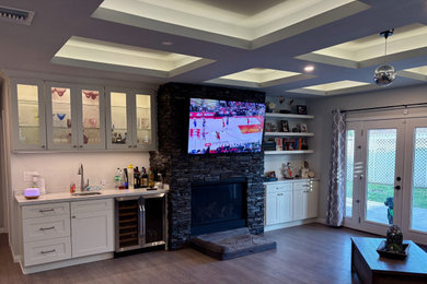 Example of a mid-sized trendy l-shaped medium tone wood floor and brown floor home bar design in Los Angeles with an undermount sink, shaker cabinets, white cabinets, quartzite countertops, gray backsplash, glass tile backsplash and white countertops