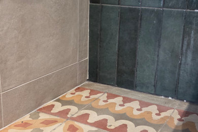 Ejemplo de cuarto de baño de nogal, único y flotante tradicional renovado de tamaño medio con armarios tipo mueble, puertas de armario de madera en tonos medios, bañera esquinera, sanitario de pared, baldosas y/o azulejos verdes, baldosas y/o azulejos de cerámica, paredes verdes, suelo de baldosas de cerámica, lavabo bajoencimera, encimera de acrílico, suelo multicolor y encimeras blancas