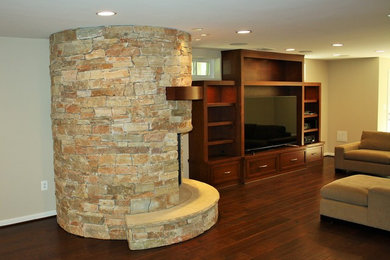 Photo of a large eclectic walk-out basement in DC Metro with beige walls, dark hardwood floors, a standard fireplace and a stone fireplace surround.