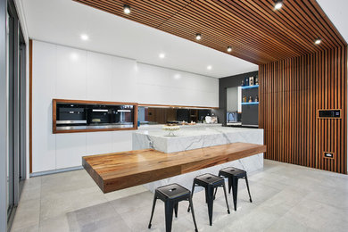 Photo of a large contemporary galley kitchen in Sydney with white cabinets, marble benchtops, with island and flat-panel cabinets.