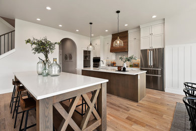 Example of a mid-sized arts and crafts medium tone wood floor and brown floor eat-in kitchen design in Boise with an undermount sink, shaker cabinets, medium tone wood cabinets, quartz countertops, multicolored backsplash, ceramic backsplash, stainless steel appliances, two islands and white countertops