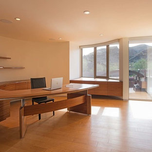 Idéer för ett mycket stort modernt hemmabibliotek, med vita väggar, mellanmörkt trägolv och ett inbyggt skrivbord