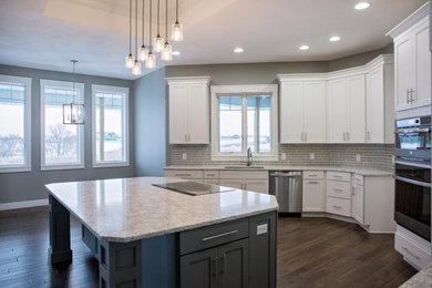 Eat-in kitchen - transitional dark wood floor, brown floor and coffered ceiling eat-in kitchen idea in Other with an undermount sink, shaker cabinets, white cabinets, granite countertops, gray backsplash, glass tile backsplash, stainless steel appliances, an island and gray countertops