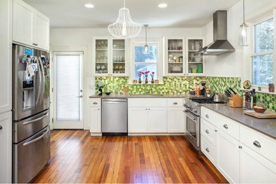 Example of a small arts and crafts l-shaped medium tone wood floor and brown floor enclosed kitchen design in Austin with an undermount sink, shaker cabinets, white cabinets, solid surface countertops, green backsplash, ceramic backsplash, stainless steel appliances, no island and brown countertops