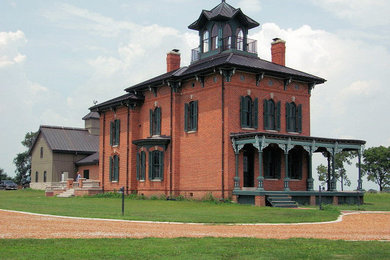Inspiration for a victorian two-story brick house exterior remodel in Other with a metal roof