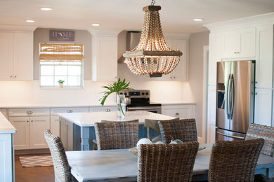 Mid-sized beach style l-shaped medium tone wood floor eat-in kitchen photo in Jacksonville with a farmhouse sink, shaker cabinets, white cabinets, quartzite countertops, white backsplash, subway tile backsplash, stainless steel appliances and an island