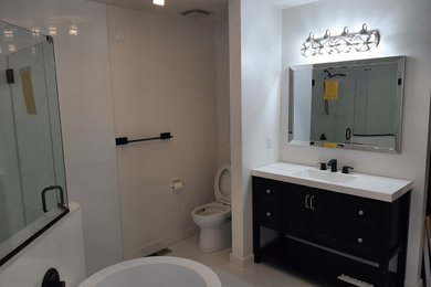 Bathroom - large master white tile porcelain tile, white floor and single-sink bathroom idea in Edmonton with furniture-like cabinets, black cabinets, solid surface countertops, a hinged shower door and a freestanding vanity