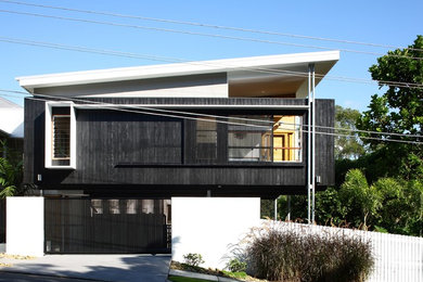 Photo of a mid-sized contemporary two-storey black exterior in Brisbane with wood siding and a shed roof.