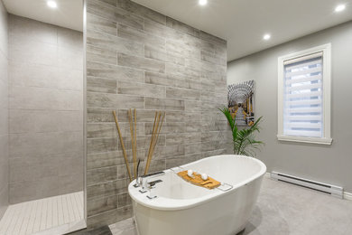 Inspiration for a contemporary master bathroom in Montreal with a freestanding tub, an open shower, gray tile, ceramic tile, grey walls, ceramic floors, a console sink, wood benchtops, grey floor and an open shower.