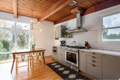 This is an example of a mid-sized midcentury l-shaped eat-in kitchen in Miami with an undermount sink, flat-panel cabinets, grey cabinets, quartzite benchtops, white splashback, subway tile splashback, stainless steel appliances, light hardwood floors, no island, brown floor, grey benchtop and wood.