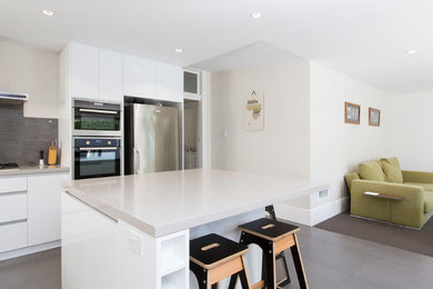 Inspiration for a mid-sized contemporary eat-in kitchen in Hobart with white cabinets, grey splashback, ceramic splashback, stainless steel appliances, ceramic floors and with island.