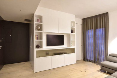 Imagen de salón contemporáneo con paredes blancas, suelo de madera clara y pared multimedia