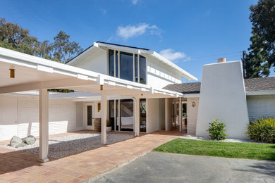 1950s white two-story brick exterior home photo in Orange County with a shingle roof