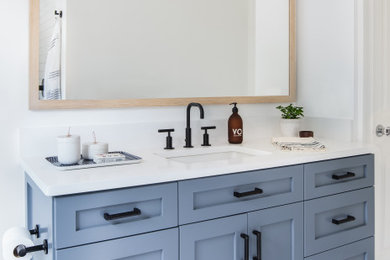 Trendy white tile and ceramic tile ceramic tile, white floor and double-sink wet room photo with white cabinets, a wall-mount toilet, white walls, an undermount sink, quartz countertops, a hinged shower door, white countertops and a niche